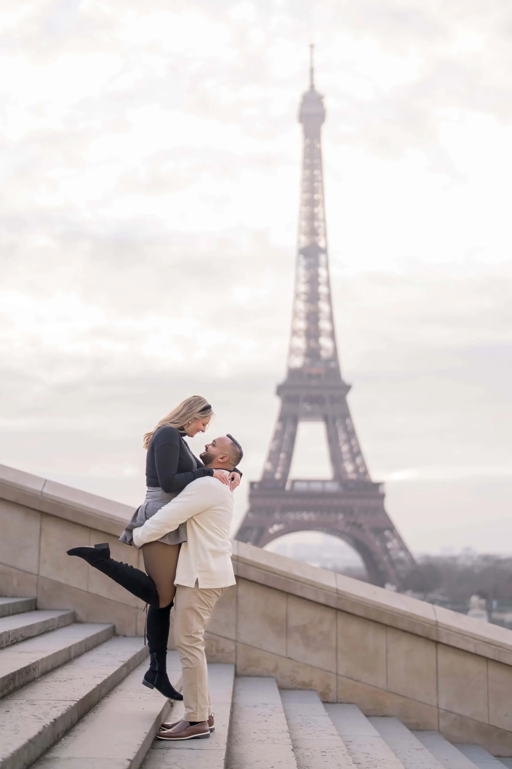 Couple fiancé s'embrassant sur les marches du Trocadéro avec vue sur la Tour Eiffel, demande en mariage dans un lieu public à Paris