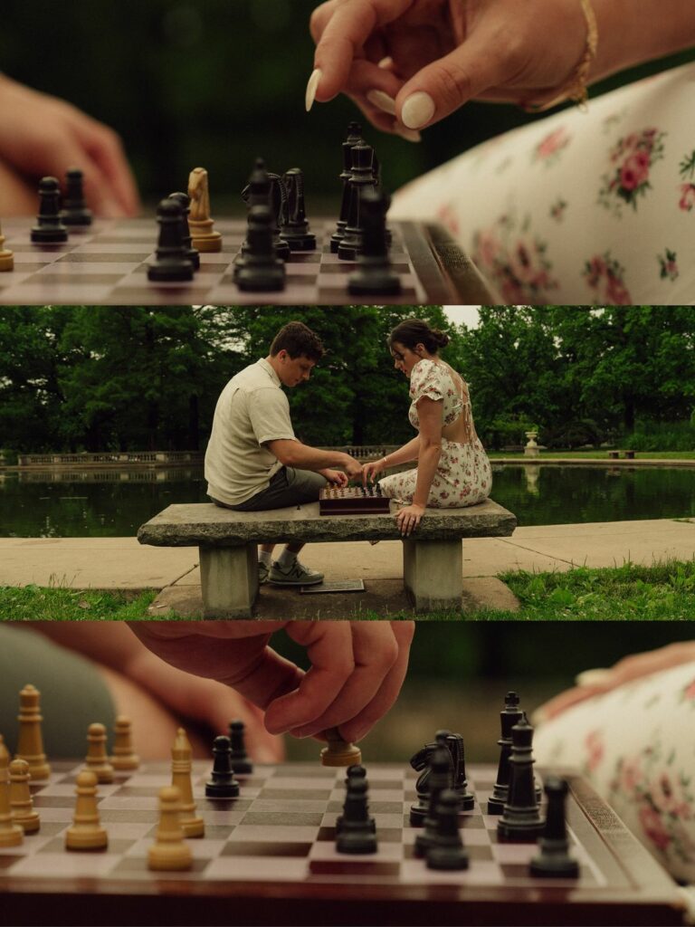 A couple playing chess on a stone bench by a lake in a lush green park.