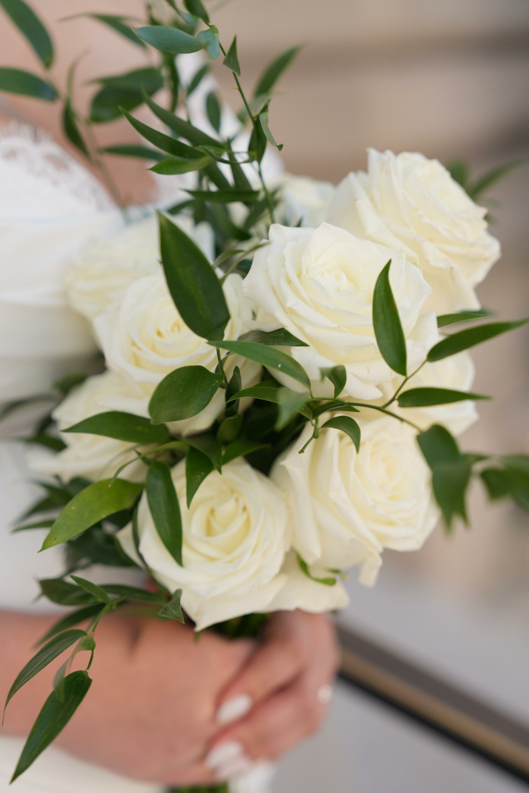Close-up of a bride holding a white rose and greenery bouquet during a Paris elopement ceremony