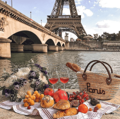 Chic Parisian picnic setup with champagne, strawberries, and pastries, celebrating a romantic engagement.