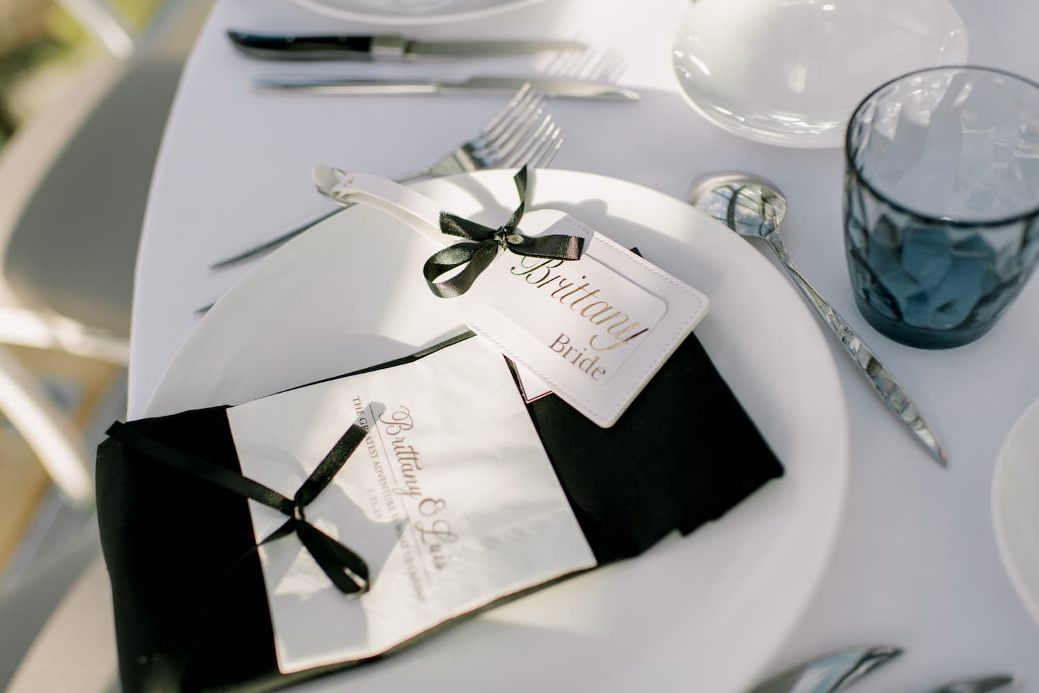 Elegant place setting with bride luggage tag and personalized menu on black napkin at a Paris micro-wedding