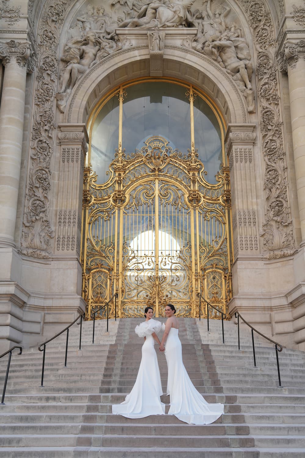 Same-sex couple holding hands on the steps of Petit Palais during their intimate Paris elopement