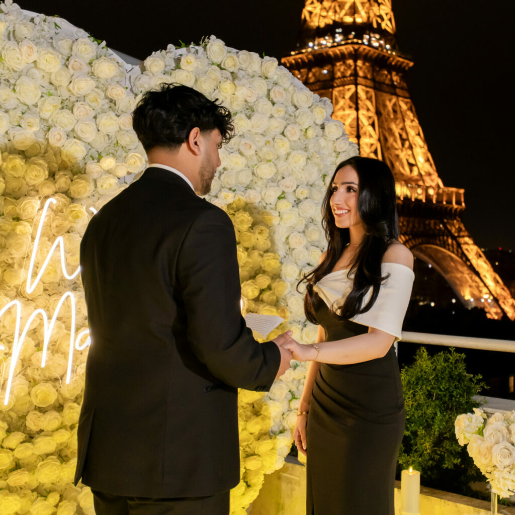 a man standing in front of her futur fiancé, telling her a handwritting speech for his proposal