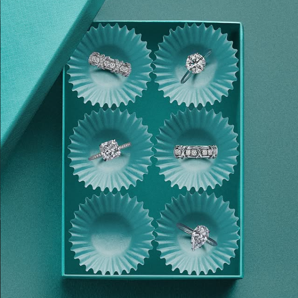 A selection of six Tiffany & Co. diamond rings displayed in a signature teal gift box, featuring solitaire, eternity and pear-cut styles — ideal engagement ring options available in Paris