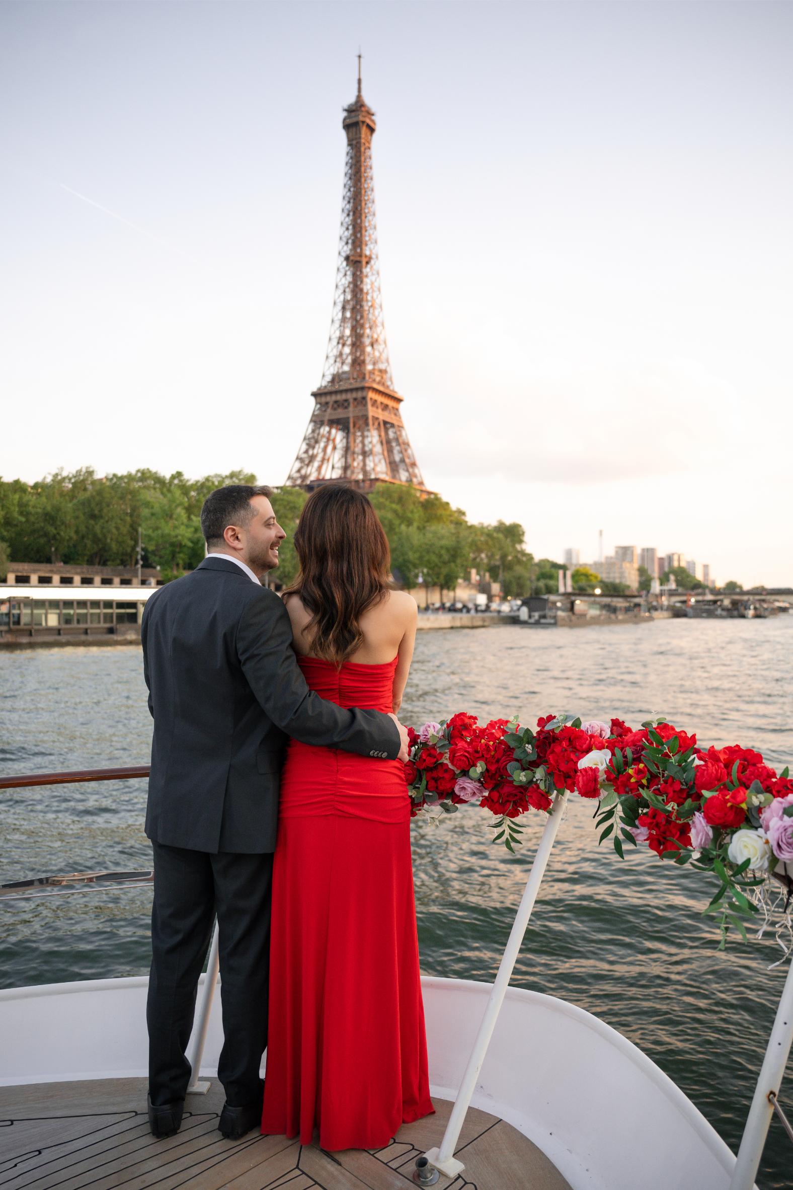 Couple enlacé sur le pont d'un bateau privatisé orné de roses rouges, face à la Tour Eiffel au coucher du soleil sur la Seine à Paris