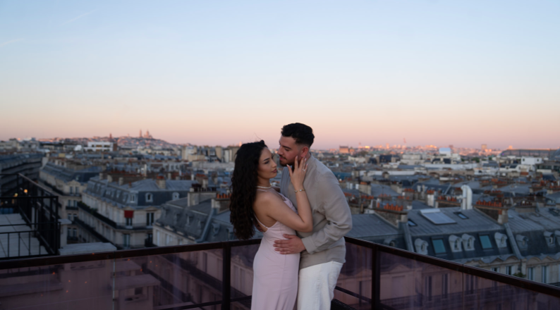 Couple s'embrassant sur un rooftop privatisé à Paris au coucher du soleil, avec les toits haussmanniens et le Sacré-Coeur en arrière-plan