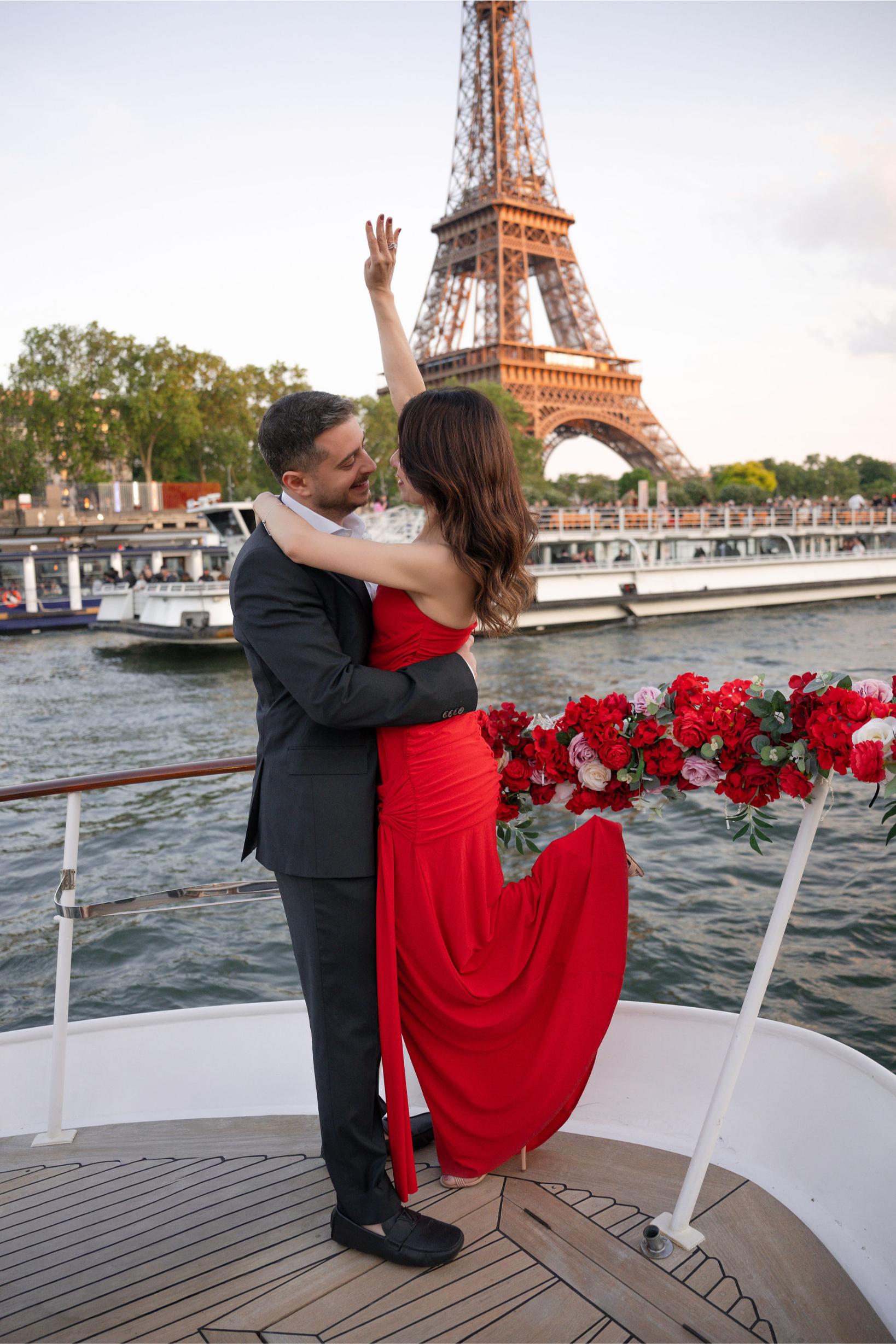 Couple embracing on a private yacht on the Seine River with the Eiffel Tower in the background after a marriage proposal in Paris