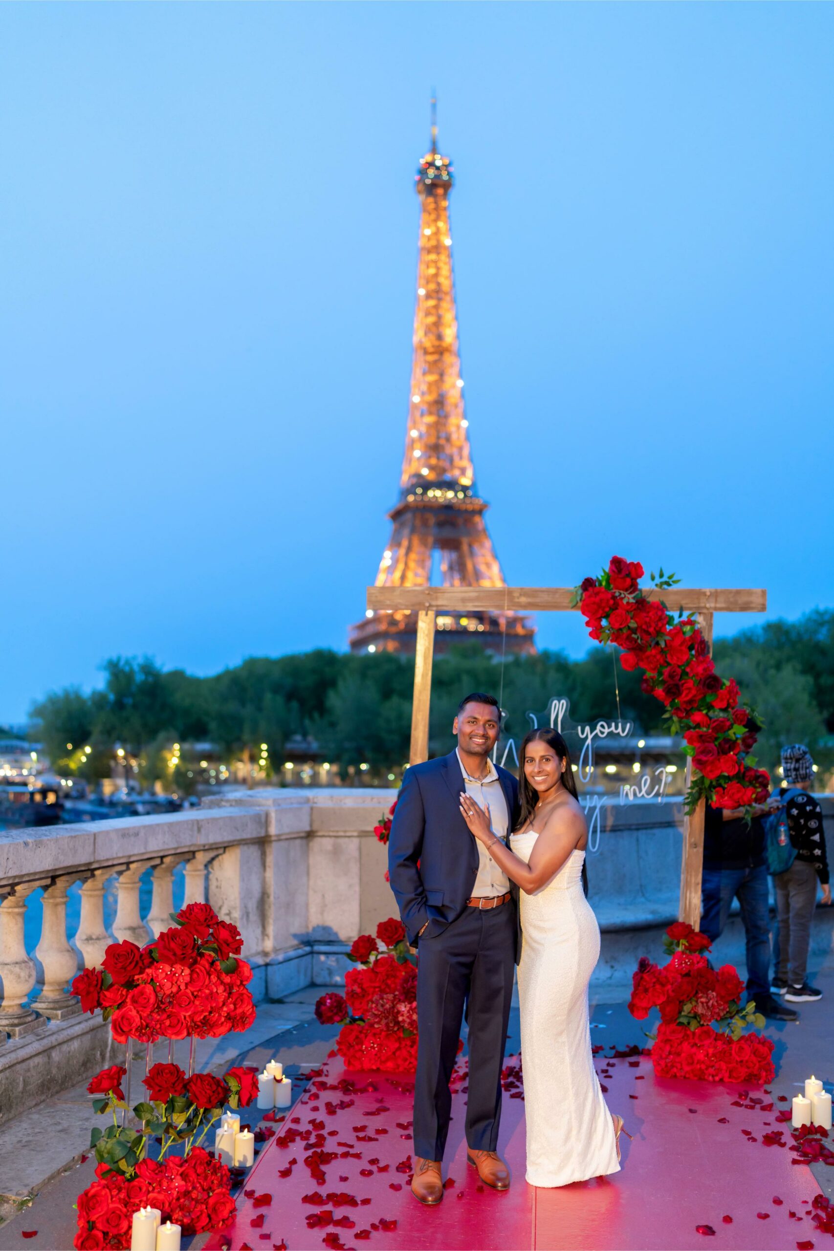 Couple after a marriage proposal on Bir-Hakeim bridge in Paris, red roses decoration and illuminated Eiffel Tower in the background