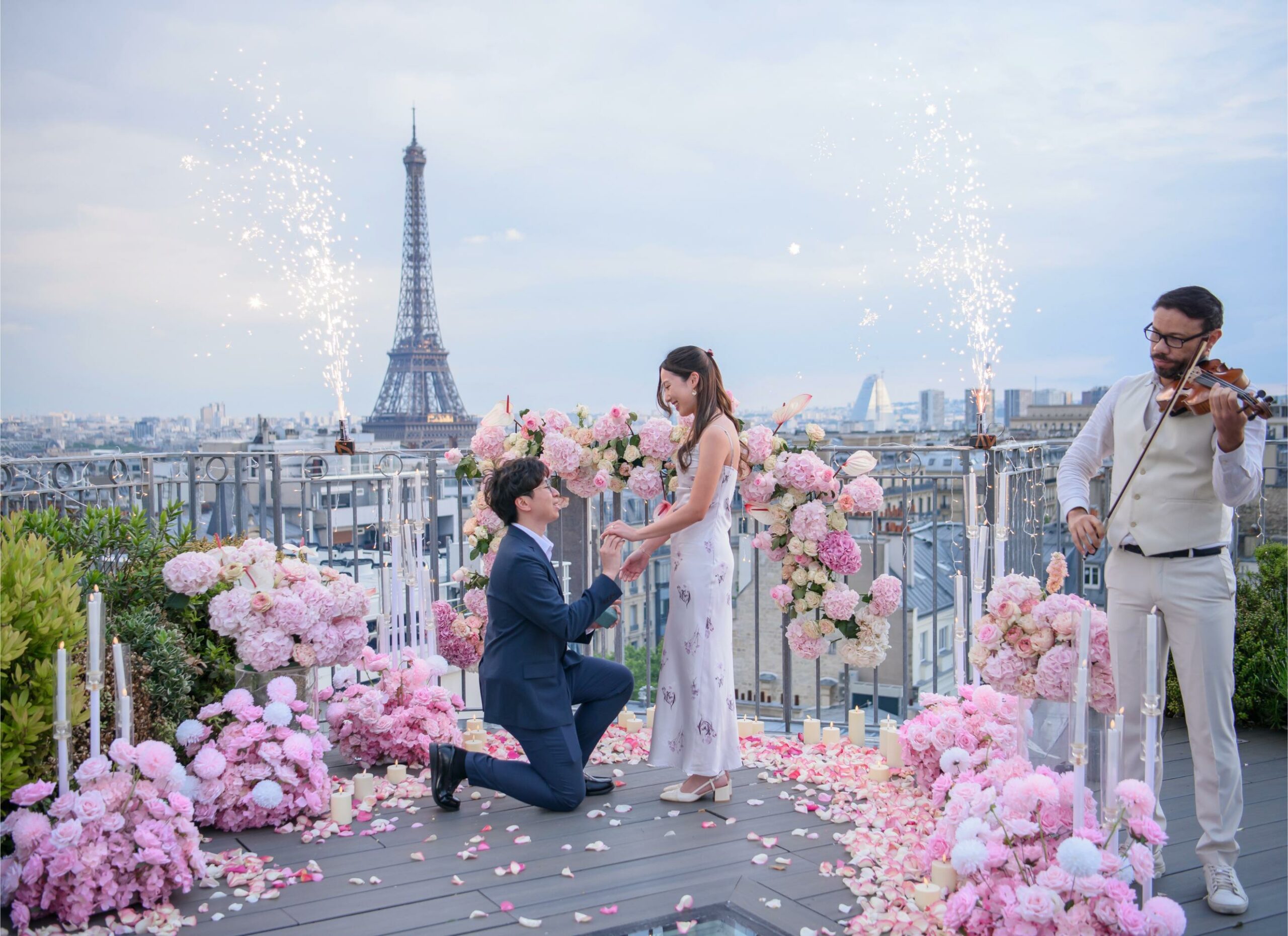 Marriage proposal on the Copernic rooftop in Paris with pink floral decorations, violinist and Eiffel Tower view at dusk