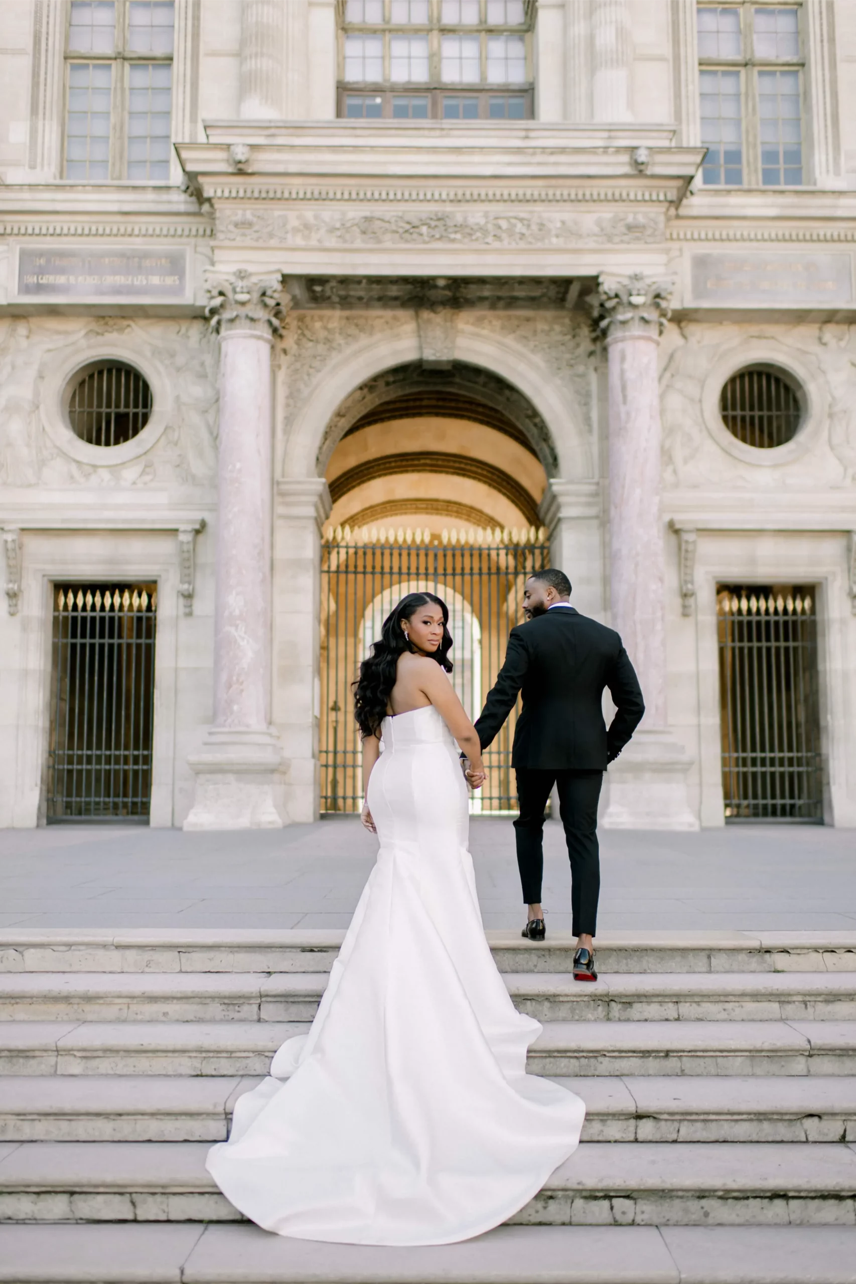 aris elopement couple walking hand in hand at the Louvre courtyard