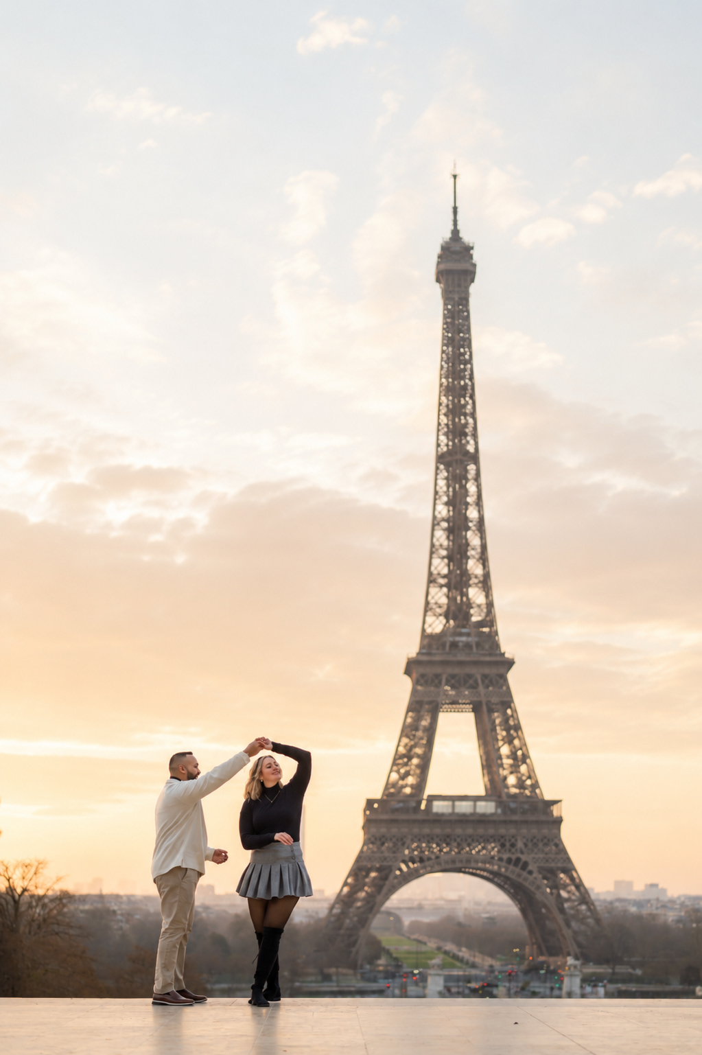 Couple dancing at Trocadéro at sunrise with the Eiffel Tower in the background, soft golden morning light over an empty esplanade in Paris