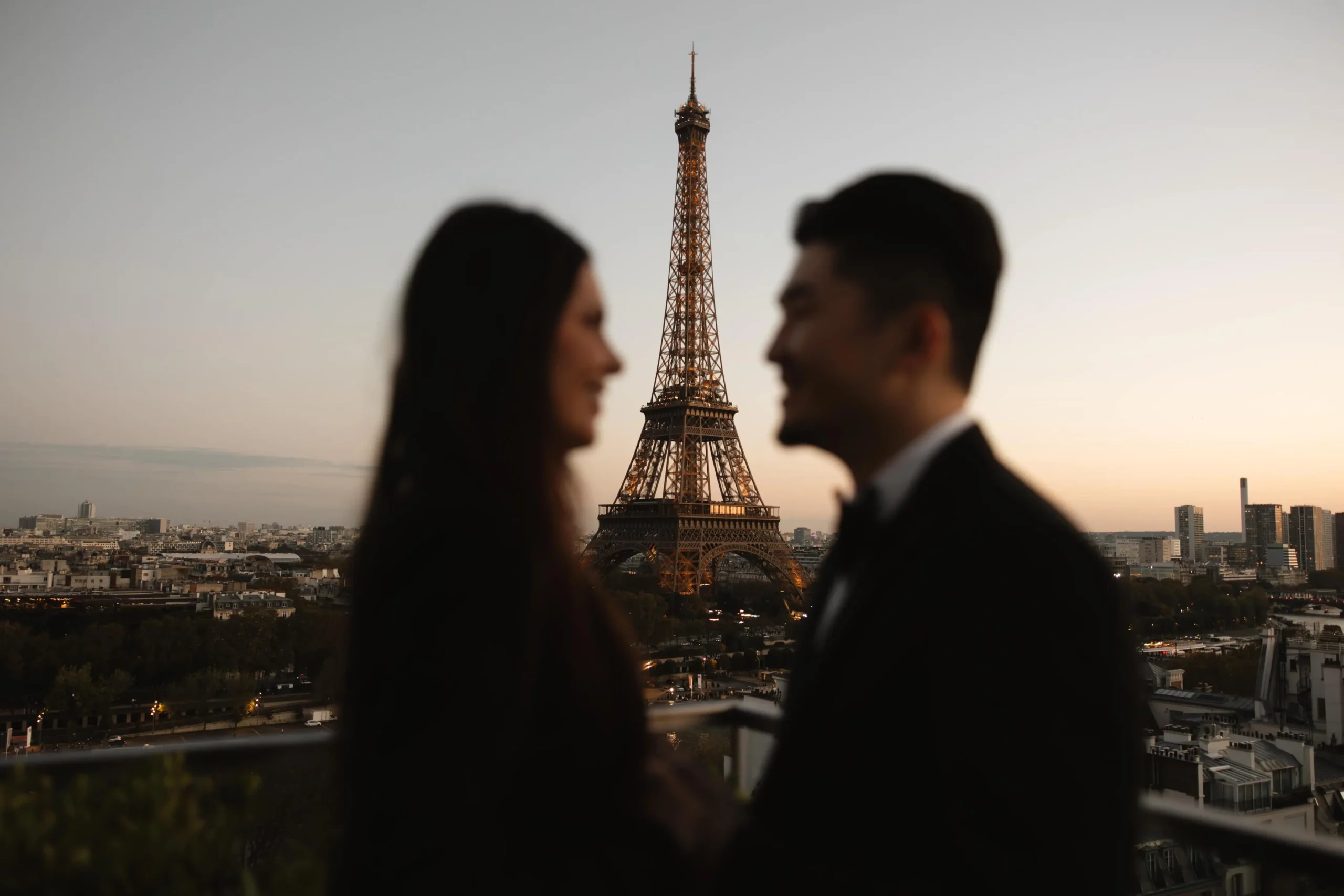 Couple on a rooftop at dusk during a romantic date night in Paris with Eiffel Tower view