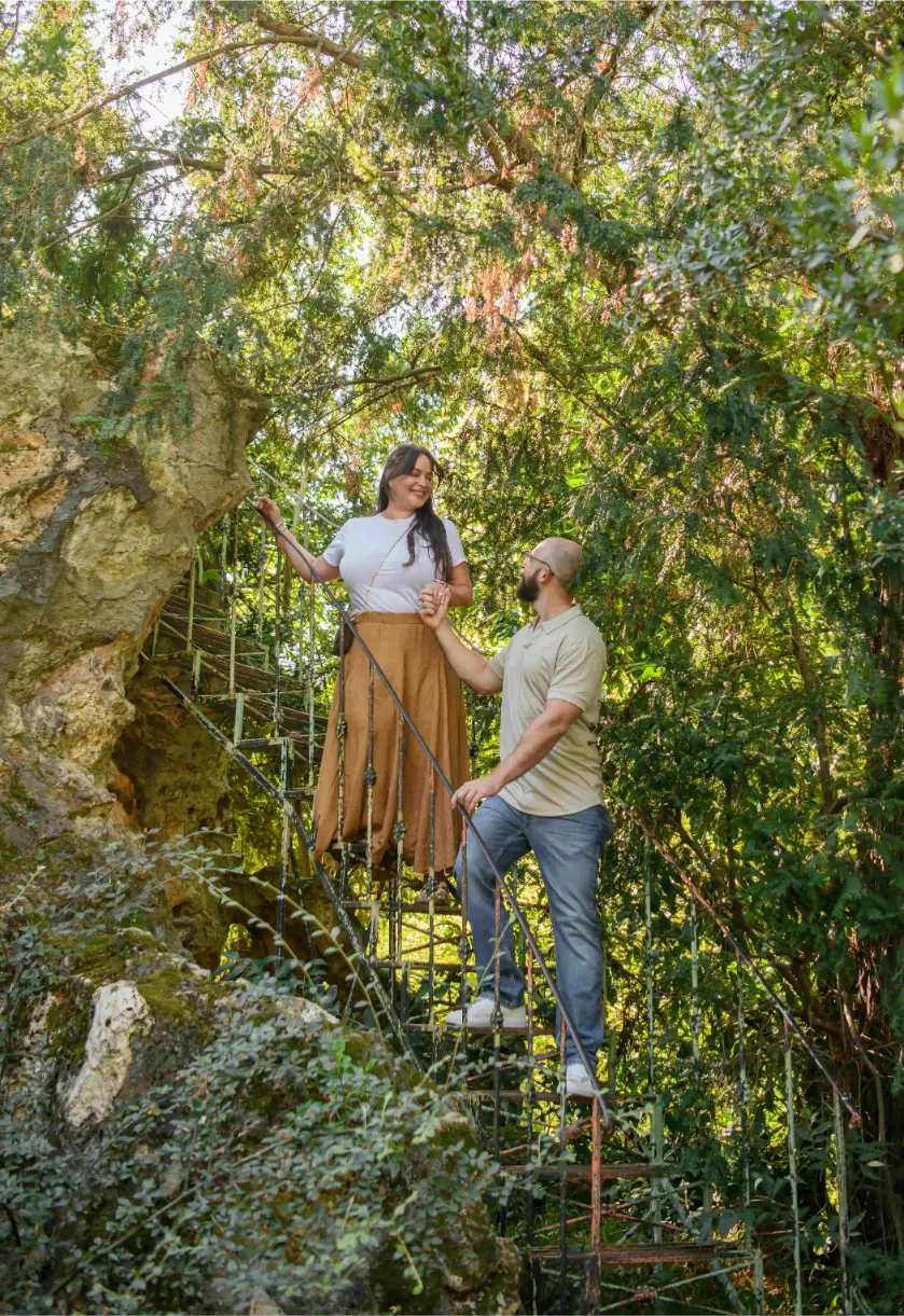 Couple walking up stone stairs near a grotto at Parc de Bagatelle garden in Paris